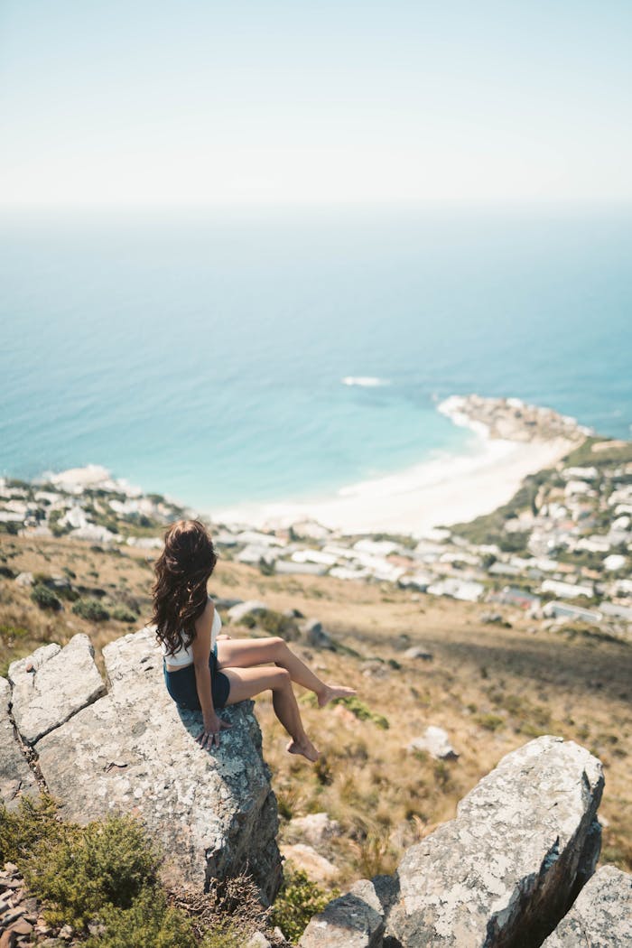 Woman enjoying a panoramic ocean view from a cliff in Cape Town, South Africa.